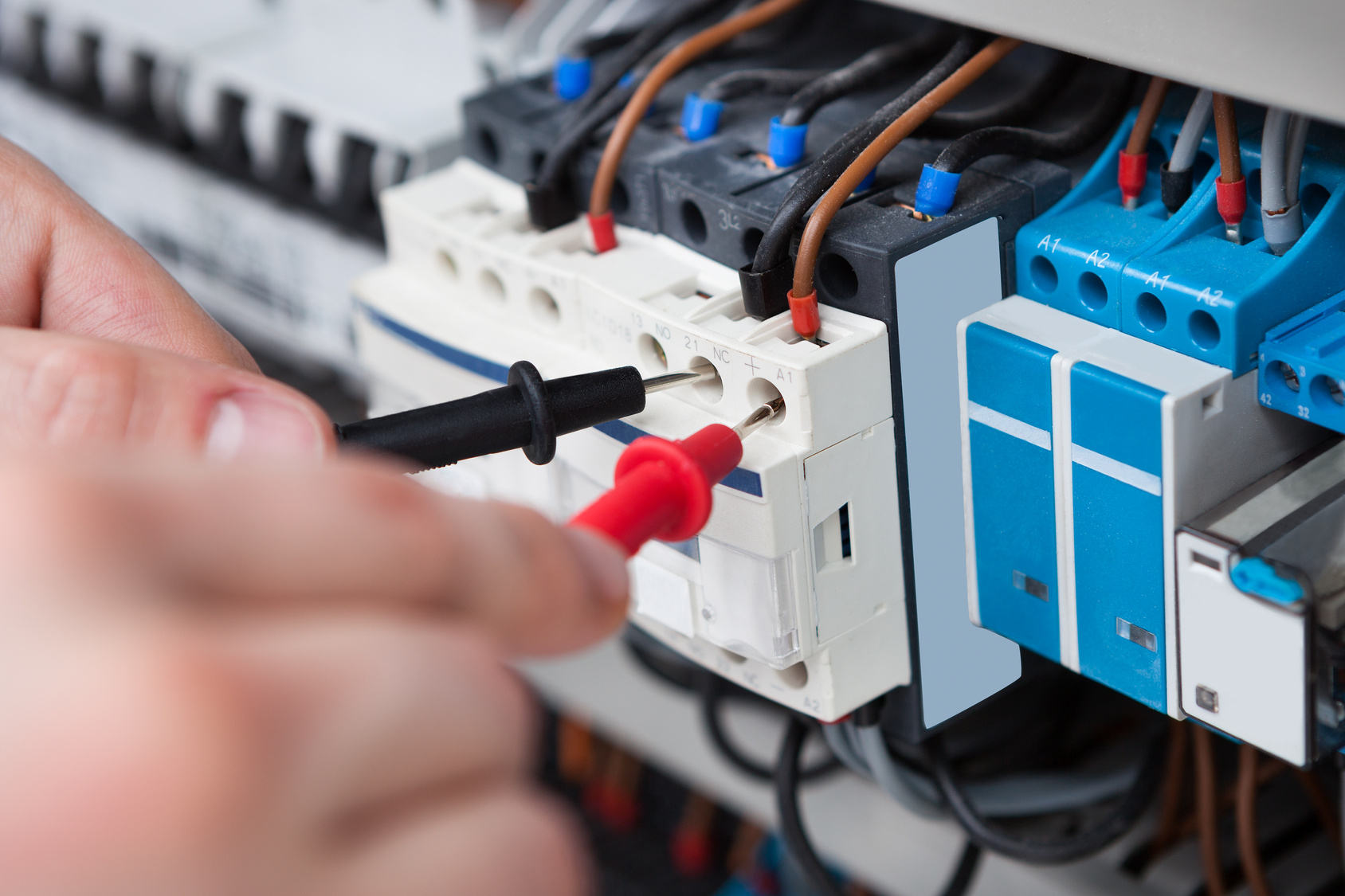 Electrician Examining Fusebox With Multimeter Probe